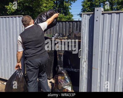 Lipetsk, Russland - 10. Juni 2018: Ein Mann wirft Plastiktüten mit Müll in einem Container Stockfoto