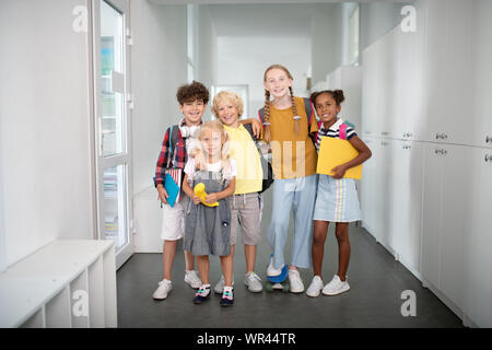 Stilvolle glückliche Schüler stehen in der Nähe der Schließfächer Alle zusammen Stockfoto