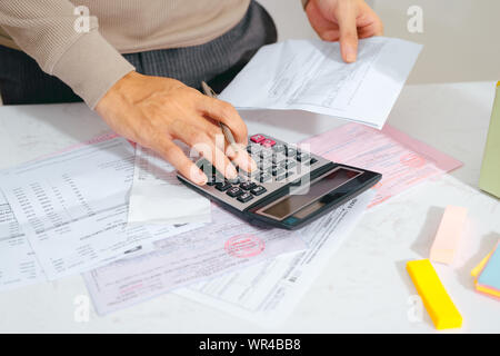 Hand Finanzen tun und auf dem Schreibtisch über Kosten zu Hause Büro berechnen. Stockfoto
