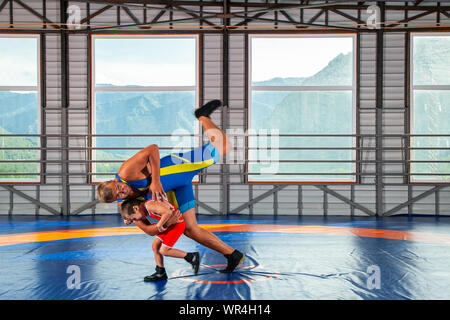 Ein erwachsenen männlichen Wrestler Trainer lehrt die Grundlagen von Ringen und stellt einen kleinen Jungen zu konkurrieren. Das Konzept der Kind macht und Martial Arts training Stockfoto