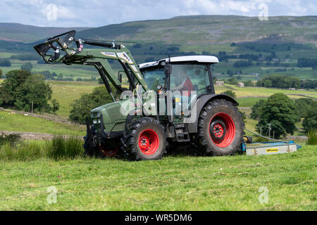 Topping überwucherte Gras auf einer Hochebene Weide mit einer Hurlimann Traktor und ein Fleming weide Topper. North Yorkshire, UK. Stockfoto