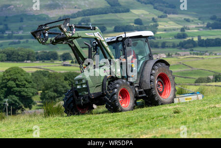 Topping überwucherte Gras auf einer Hochebene Weide mit einer Hurlimann Traktor und ein Fleming weide Topper. North Yorkshire, UK. Stockfoto