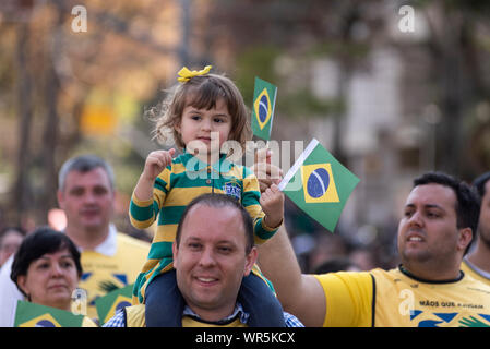 07. September 2019, Brasilien, Curitiba: Ein kleines Mädchen hält eine brasilianische Flagge und Uhren eine Parade auf den Schultern ihres Vaters Brasiliens Unabhängigkeit zu feiern. Die Parade wurde von Schulen und Zivilisten sowie die brasilianischen Streitkräfte - die Armee, die Marine und Luftfahrt besucht. Dies ist die erste Militärparade seit der Amtseinführung von Präsident Bolsonaro. Foto: Henry Milleo/dpa Stockfoto