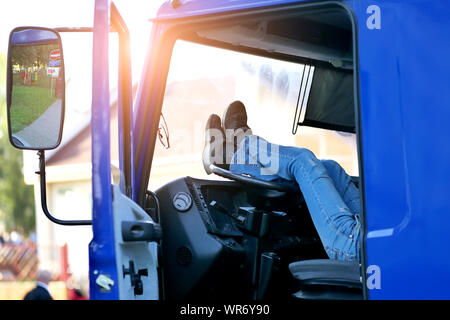 Der LKW-Fahrer ruht in der Kabine des Auto mit seinen Füßen auf dem Lenkrad Stockfoto