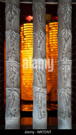 Tausende von Kerzen in der Rückseite eines taoistischen Tempel in Taipei, Taiwan. Stein Bambus Trunks in der Front. Stockfoto