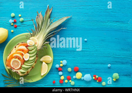 Draufsicht auf pienapple Boote mit geräuchertem Lachs und Avocado Schichten mit Zitrone und Wachteleier, flach auf Türkis strukturierten Hintergrund legen Stockfoto