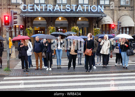 Göteborg, Schweden - 3. September 2019: Menschen beim Zebrastreifen vor dem Hauptbahnhof warten mit umbrrallas im Regen für ein grünes Licht. Stockfoto