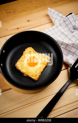 Leckeren Toast mit Spiegelei in der Pfanne auf hölzernen Küchentisch Stockfoto