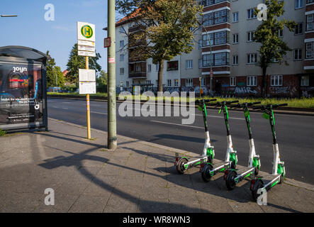 Kalk e-Scooter an einer Bushaltestelle im Bereich Berlin Neukölln geparkt, Deutschland Stockfoto