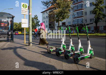 Kalk e-Scooter an einer Bushaltestelle im Bereich Berlin Neukölln geparkt, Deutschland Stockfoto