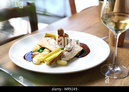 Hähnchenfleisch gefüllt mit Gorgonzola, serviert mit Lauch in Butter gebraten, Knödel, grüne Erbsen und Rotweinsauce. Stockfoto