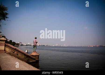 Ein Fischer am Rande des West Lake in Hanoi, Vietnam. Stockfoto