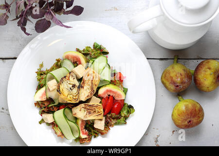 Eine leichte vegetarische Salat mit Feigen, Artischocken, Gurken, Tomaten, Feta auf Rucola Blätter, gekrönt mit Himbeersauce. Stockfoto