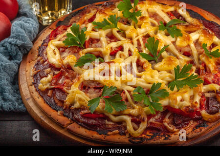 Hausgemachte Pizza mit Fleisch, Wurst, Käse und Tomaten Stockfoto