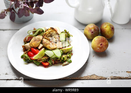 Eine leichte vegetarische Salat mit Feigen, Artischocken, Gurken, Tomaten, Feta auf Rucola Blätter, gekrönt mit Himbeersauce. Stockfoto