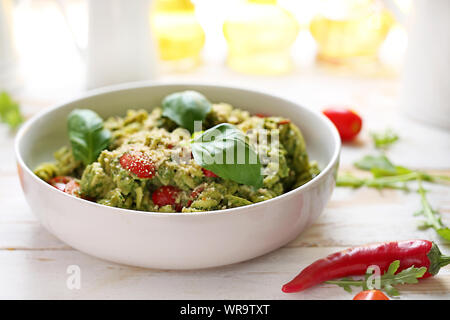 Nudeln mit Spinat und Tomaten. Einen Teller auf einem weißen Tisch Stockfoto