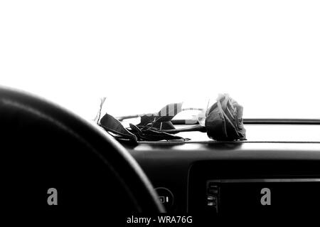 Ein Schwarz/Weiß-Darstellung einer Rose Blume liegt auf dem Armaturenbrett im Auto Stockfoto