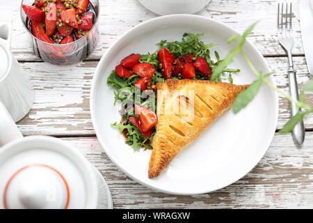 Ravioli mit Ricotta Torte gebacken serviert mit Rucola Salat und Erdbeeren in Aceto Balsamico mit grünem Pfeffer. Stockfoto