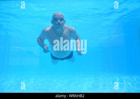 Man schwimmt unter Wasser in einem Pool in seiner Unterhose. Freizeitaktivitäten Stockfoto