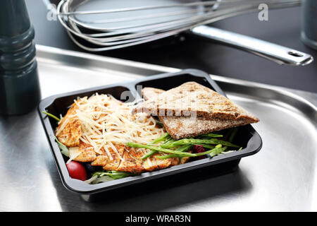 Essen zum Mitnehmen in eine Box. Hähnchenfilet mit Vollkornbrot und Gemüse Stockfoto