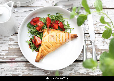 Ravioli mit Ricotta Torte gebacken serviert mit Rucola Salat und Erdbeeren in Aceto Balsamico mit grünem Pfeffer. Stockfoto