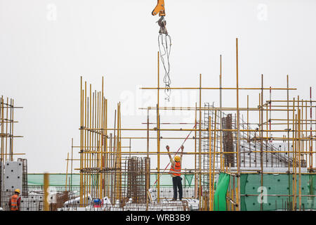 Chinesische Wanderarbeiter bauen ein Wohngebiet Apartment Gebäude unter der sengenden Sonne steigen bei einer lokalen Slum Abstand und Gehäuse renovat Stockfoto