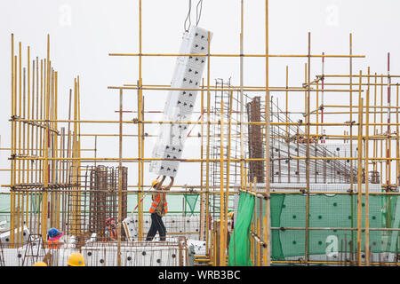 Chinesische Wanderarbeiter bauen ein Wohngebiet Apartment Gebäude unter der sengenden Sonne steigen bei einer lokalen Slum Abstand und Gehäuse renovat Stockfoto