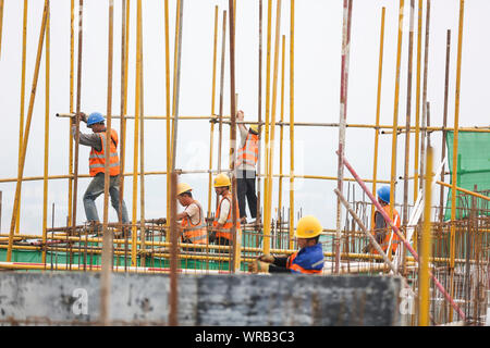 Chinesische Wanderarbeiter bauen ein Wohngebiet Apartment Gebäude unter der sengenden Sonne steigen bei einer lokalen Slum Abstand und Gehäuse renovat Stockfoto