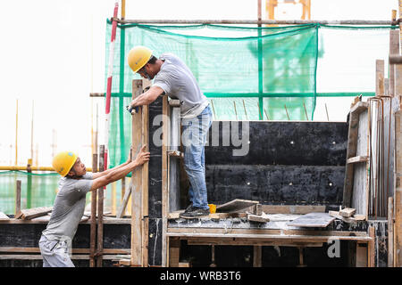 Chinesische Wanderarbeiter bauen ein Wohngebiet Apartment Gebäude unter der sengenden Sonne steigen bei einer lokalen Slum Abstand und Gehäuse renovat Stockfoto