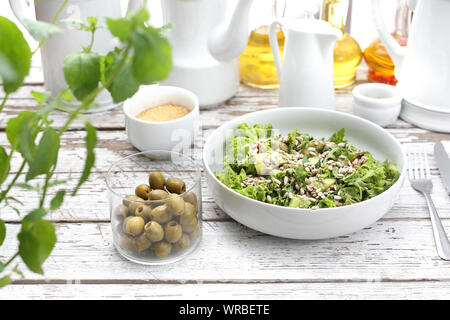 Frischer Salat mit Oliven, getrocknete Tomaten, Sonnenblumenkerne mit einer Sauce auf der Basis von Öl und Kräutern serviert. Stockfoto