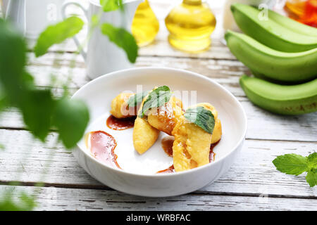 Bananen gebraten mit Karamellsauce und Kokosraspeln. Süße Nachspeise. Stockfoto