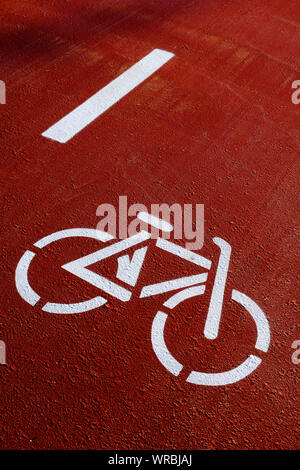 Nahaufnahme von einem Radweg, dargestellt von der Silhouette eines weißen Fahrrad auf ein rotes Pflaster Stockfoto