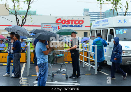 Die Menschen warten im Regen außerhalb der Costco Store in Shanghai, China, am 29. August, 2019. Us-handelskette Riese Costco angekündigt Shopp zu begrenzen. Stockfoto