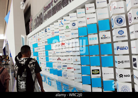 Besucher sehen die Logos der Teilnehmer unternehmen während Smart China Expo 2019 (SCE 2019) in Chongqing, China am 27.August 2019. Insgesamt 530 Stockfoto