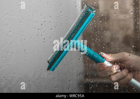 Nahaufnahme Reinigung dusche Glastür mit Rakel Stockfoto