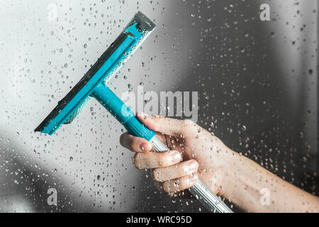 Nahaufnahme Reinigung dusche Glastür mit Rakel Stockfoto