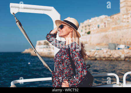 Glückliche junge blonde Frau in hat mit der Fähre Schiff auf dem Mittelmeer unterwegs Stockfoto