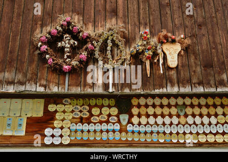 Getrocknete Blumen für Almabtrieb und Auszeichnungen auf Metall Abzeichen für Milchkühe zu einem hölzernen Scheune angebracht. Traditionelle Rinderhaltung, Österreich. Stockfoto