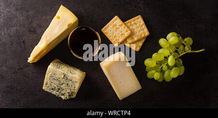 Auswahl an Käse und Wein auf schwarzem Hintergrund. Panorama Ansicht Stockfoto