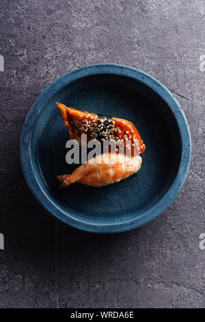 Overhead Bild von zwei Sushi serviert auf einem Teller. Garnelen und unagi auf konkreten Hintergrund Stockfoto