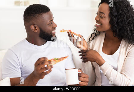 Schöne afrikanische amerikanische Paar teilen Pizza am Tag zu Hause. Stockfoto