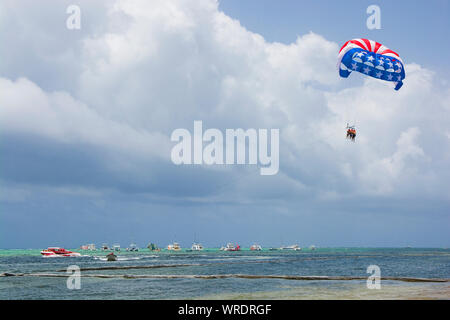 Amerikanische Flagge Farben parasail Flügel fliegen über türkisfarbenem Wasser der Sargassosee, Punta Cana, Dominikanische Republik Stockfoto