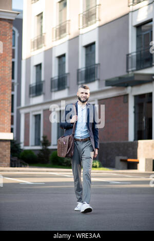 Bärtiger Mann verlassen und zu Fuß zum Büro Stockfoto