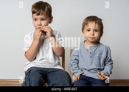 Kinder in der Cafeteria sitzen beim essen zu Mittag. Lächelnde Kinder mit Sandwiches. Pizza in der Schule. Essen zusammen. Stockfoto