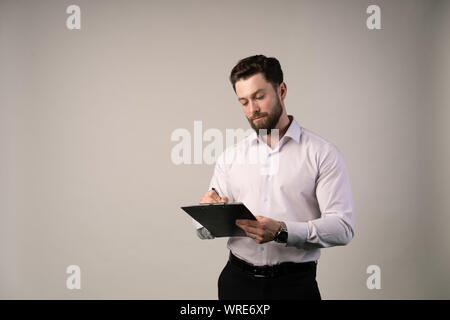 Mittleres Alter, 30-40 s Geschäftsmann Unterzeichnung offizieller Vertrag oder Befüllung Business Document mit einem Stift, der in modernen Büro bei einer Tasse Kaffee, in der Nähe u Stockfoto