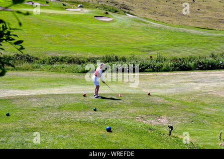 Eine Frau mittleren Alters, die Golf im Golfclub Courmayeur und Grandes Jorasses von Val Ferret, einem Tal am Fuße des Mont Blanc Massivs, Alpen, Italien Stockfoto