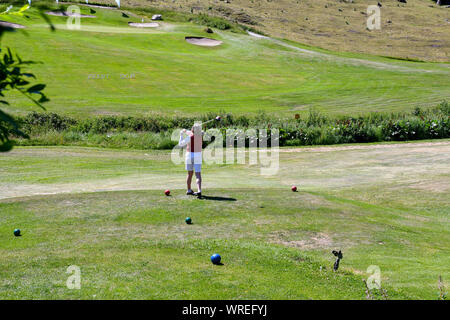 Eine Frau mittleren Alters, die Golf im Golfclub Courmayeur und Grandes Jorasses von Val Ferret, einem Tal am Fuße des Mont Blanc Massivs, Alpen, Italien Stockfoto