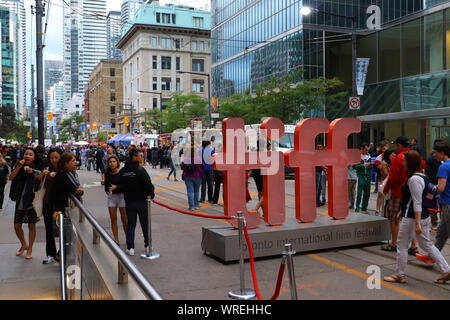 TIFF 2019 Fans zu Fuß auf der King St West in Toronto neben dem TIFF-Zeichen. Stockfoto