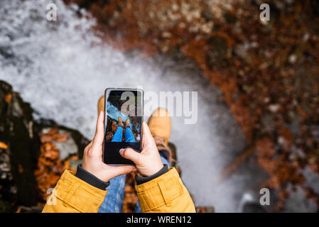 Die Frau am Telefon Ihrer Beine mit Wasserfall im Hintergrund Stockfoto