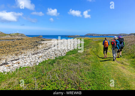 3 Personen zu Fuß in Richtung große Bucht und die daymark auf St. Martin's Island, Isles of Scilly, Cornwall, England, Großbritannien Stockfoto